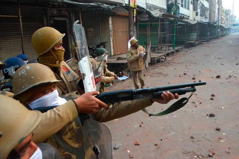 A police personnel aims his gun towards protesters during demonstrations against India's new citizenship law in Kanpur. AFP