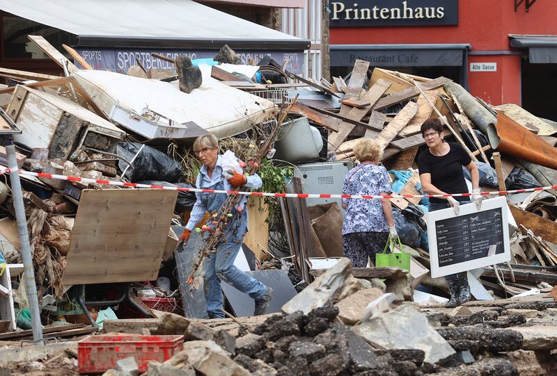 People carry items while attempting to clear an area affected by floods caused by heavy rainfall in Bad Muenstereifel, Germany.