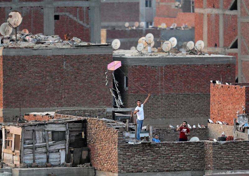 Men fly a handmade kite from a roof, following the outbreak of the coronavirus, in Cairo, Egypt.  Reuters