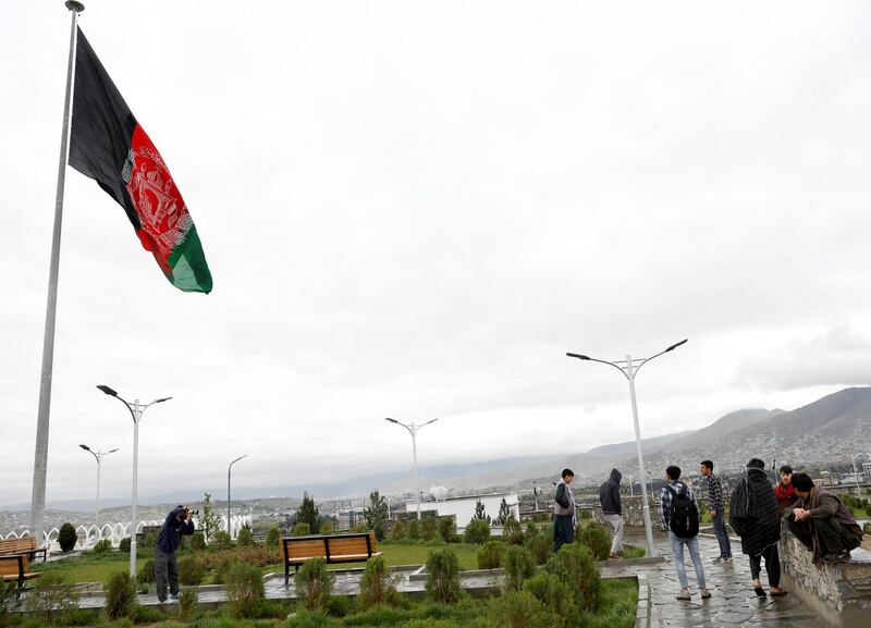 Youths take pictures near an Afghan flag on a hilltop overlooking Kabul, Afghanistan, April 15. Reuters
