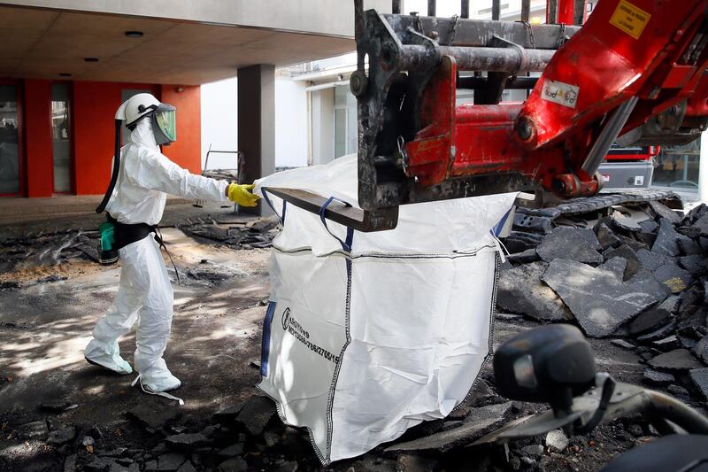 Worker directs a mechanical shovel grabbing pieces of destroyed surfacing to gather up the lead particles in the school yard of Saint Benoit primary school in Paris, France. AP photo