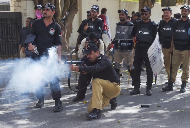 A Pakistani policeman fires teargas shell toward government teachers during a protest in Karachi on March 28, 2019. Government teachers were protesting outside Karachi Press Club while police took an action against them as they march towards the 'Red Zone' demanding regularisation of their contracts and change in their time cycle. / AFP / ASIF HASSAN
