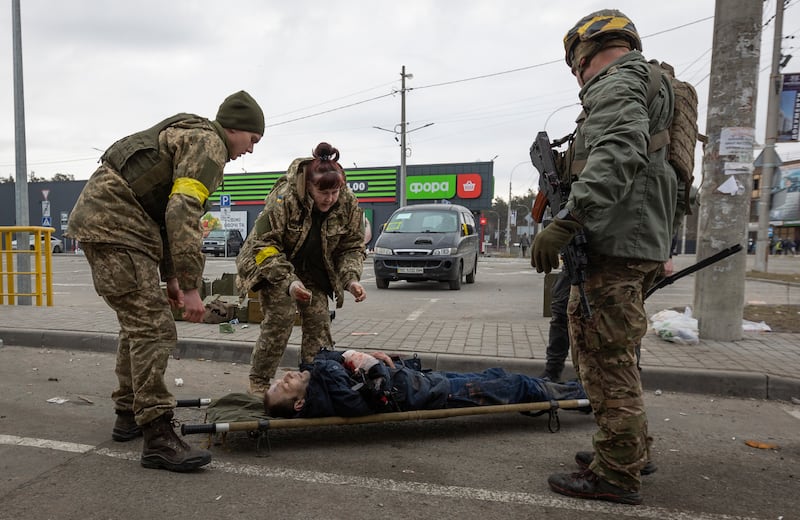 Ukrainian servicemen put a wounded man on a stretcher in Irpin.  AP Photo