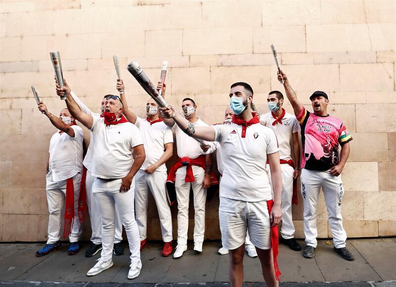Several 'mozos' or runners wearing the traditional outfit chant in front of a St Fermin sculpture in Pamplona, northern Spain. The traditional bull-running festival has been cancelled because of the coronavirus pandemic.  EPA