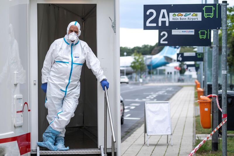 A person in protective clothes stand in the entrance of test station for the coronavirus at Cologne/Bonn Airport in Cologne, Germany.  AP