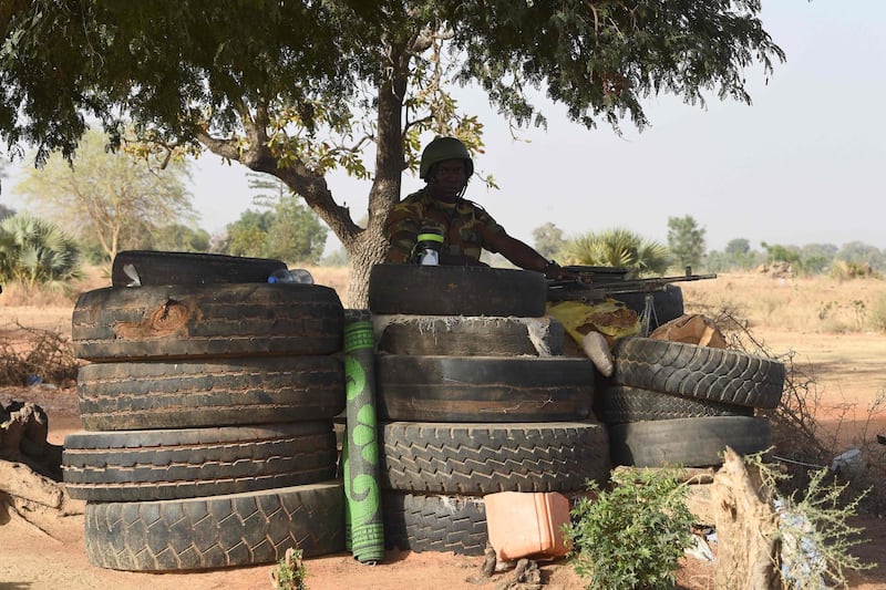 A Togolese soldier holding a machine gun keeps watch under a tree surrounded by used tyres as he monitors proceedings at Yemboate, the northern Togo border post with Burkina Faso, on February 17, 2020. Togolese security agencies have intensified surveillance around border with neighbouring Burkina Faso, and with strong army presence to check and prevent incursion of Jihadists into the country. / AFP / PIUS UTOMI EKPEI
