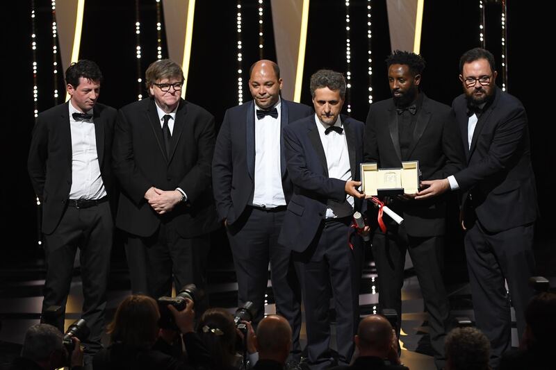 Christophe Barral, Toufik Ayadi, Kleber Mendonca Filho, Ladj Ly and Juliano Dornelles, winners of the Jury Prize award for their films "Les Miserables" and "Bacurau" pose with Michael Moore on stage at the Closing Ceremony during the 72nd annual Cannes Film Festival on May 25, 2019 in Cannes, France. Getty Images