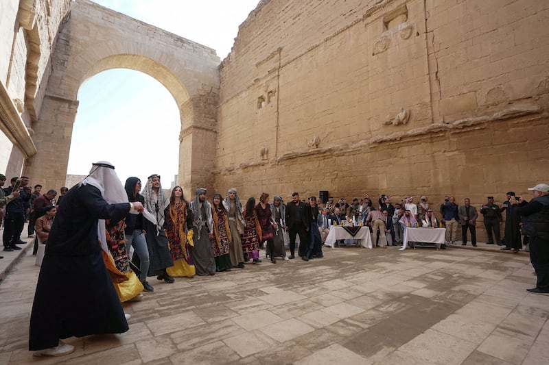 Iraqis perform a traditional dance during the ceremony to unveil restored sculptures at the site. AFP