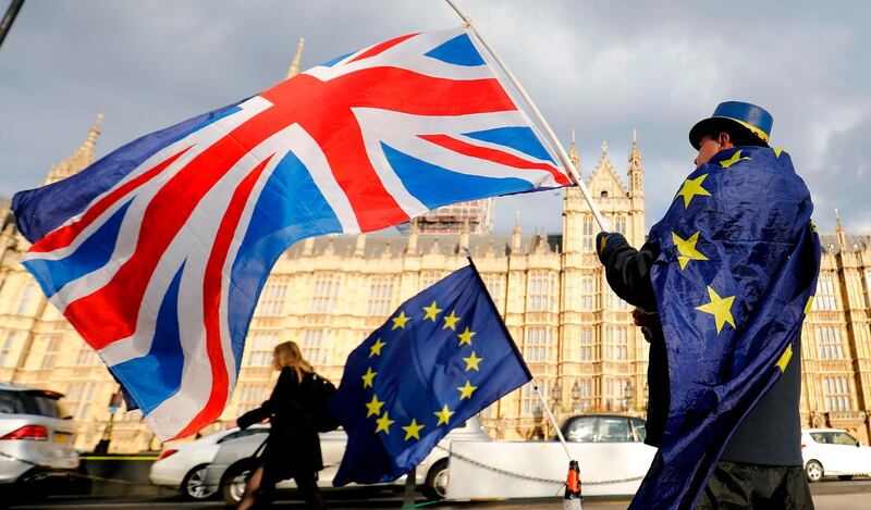 (FILES) In this file photo taken on March 28, 2018 An anti-Brexit demonstrator waves a Union flag alongside a European Union flag outside the Houses of Parliament in London. The British government said on September 7, 2020, that it was taking steps to "clarify" how Northern Ireland's trade will be handled after Brexit, but insisted it remained committed to its EU withdrawal agreement and the province's peace process. Britain cannot allow the peace process or its internal market "to inadvertently be compromised by unintended consequences" of the Brexit protocol relating to Northern Ireland, Prime Minister Boris Johnson's official spokesman said.
 / AFP / Tolga AKMEN
