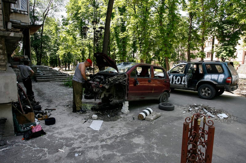 A man repairs a car in a residential area of Mariupol. AFP