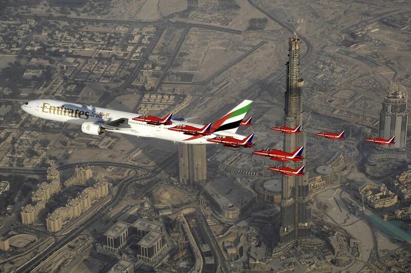 An Emirates Boeing 777 is escorted by jets from the UK's royal air force Red Arrows display team over Dubai. Red Arrows Cpl Andy Benson / AP