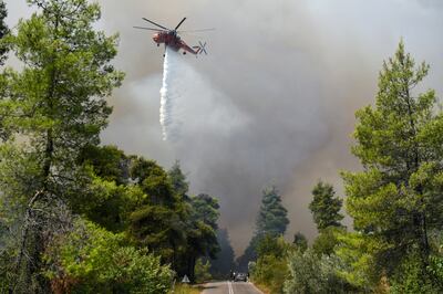 A helicopter drops water from the air to tackle a fire burning near the village of Ellinika, on the island of Evia, Greece. Reuters 