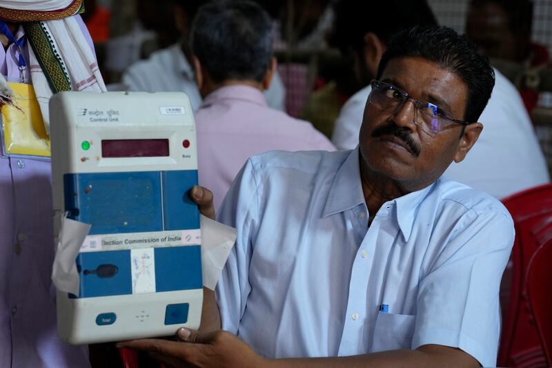An election official displays an electronic voting machine after unsealing it to count votes in Lucknow. AP