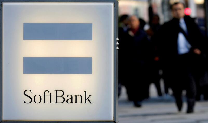 FILE PHOTO: People walk behind the logo of SoftBank Corp in Tokyo December 18, 2014.  REUTERS/Toru Hanai/File Photo