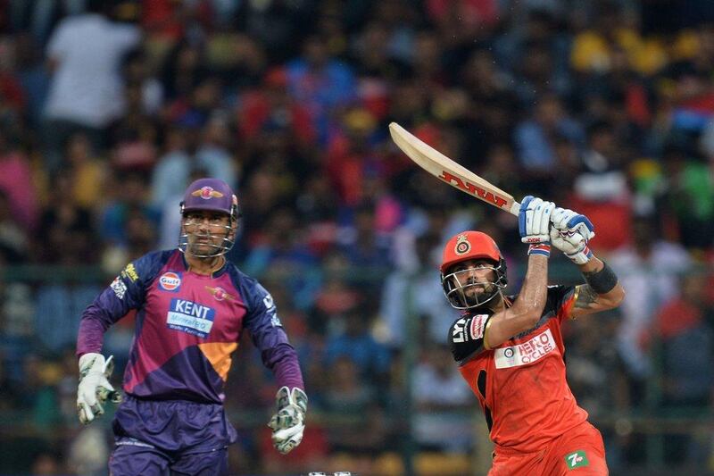 Royal Challengers Bangalore captain and batsman Virat Kohli (R) plays a shot while Rising Pune Supergiants captain and wicketkeeper MS Dhoni looks on during the 2016 Indian Premier League (IPL) Twenty20 cricket match between Royal Challengers Bangalore and Rising Pune SuperGiants, at The M Chinnaswamy Stadium in Bangalore on May 7, 2016. Royal Challengers Bangalore are chasing a target of 192 runs set by Rising Pune SuperGiants. Manjunath Kiran / AFP