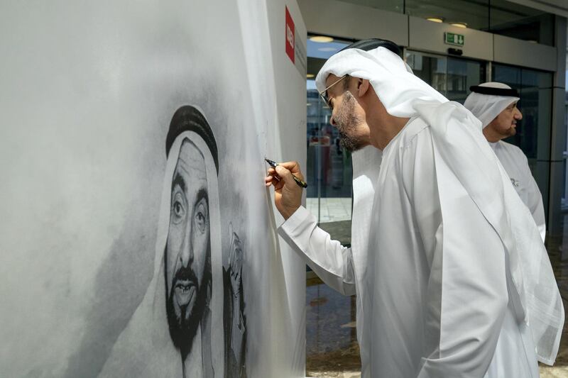 AL AIN, ABU DHABI, UNITED ARAB EMIRATES - February 07, 2019: HH Sheikh Mohamed bin Zayed Al Nahyan, Crown Prince of Abu Dhabi and Deputy Supreme Commander of the UAE Armed Forces (C), sings a portrait of HH Sheikh Zayed bin Sultan bin Zayed Al Nahyan, during a visit to the United Arab Emirates University. 
( Ryan Carter for the Ministry of Presidential Affairs )
---