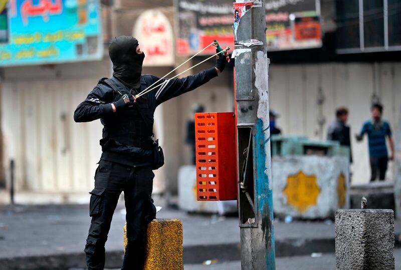 An anti-government protester uses a slingshot to fire a stone at security forces during clashes in Baghdad, Iraq. AP Photo