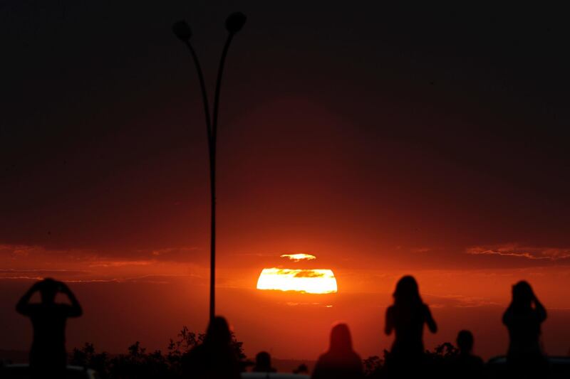 People watch the sunset before a partial lunar eclipse in the skies of Brasilia, Brazil. AP Photo/Eraldo Peres