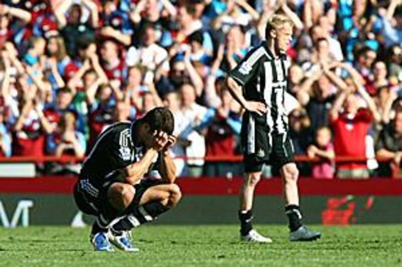 Newcastle's Steven Taylor, left, crouches on the ground while teammate Damien Duff walks off the pitch after their 1-0 defeat to Aston Villa meaning relegation for the club.