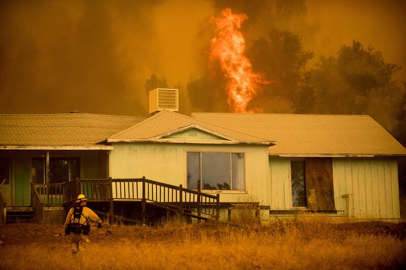 Flames rise behind a vacant house as a firefighter works to halt the Detwiler fire near Mariposa, California. Noah Berger / AP Photo