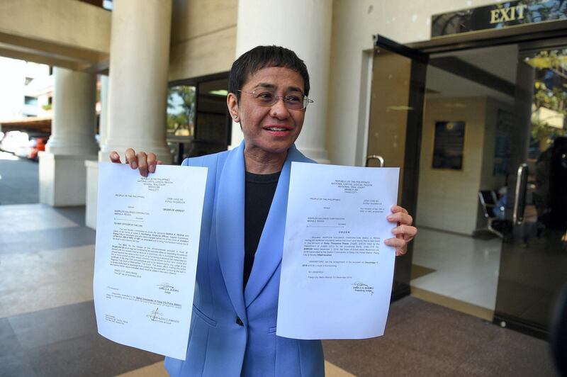Maria Ressa, CEO and executive editor of online portal Rappler shows the warrant of arrest order after posting bail at a court in Manila on December 3, 2018. - The journalist who leads a news site that has battled Philippine President Rodrigo Duterte paid a cash bail on December 3 on a tax fraud charge she says is an effort to intimidate the publication. (Photo by Ted ALJIBE / AFP)