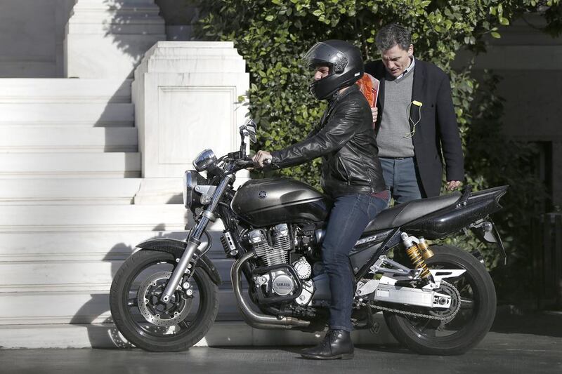 The Greek finance minister, Yanis Varoufakis, left, and deputy Foreign minister for international economic relations, Euclid Tsakalotos, prepare to leave on a motorcycle from the office of the Greek prime minister Alexis Tsipras in Athens on Friday. The ministers met as the country faces a mounting challenge to meet its debt obligations and talks with rescue creditors have so far failed to break an impasse over future cost-cutting reforms. Petros Giannakouris / AP Photo