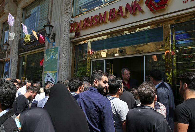 Iranians stand in front of a bank, hoping to buy U.S. dollars at the new official exchange rate announced by the government, in downtown Tehran, Iran, Tuesday, April 10, 2018. Iran moved on Tuesday to enforce a single exchange rate to the dollar, banning all unregulated trading after the country's currency, the rial, hit an all-time low. (AP Photo/Vahid Salemi)