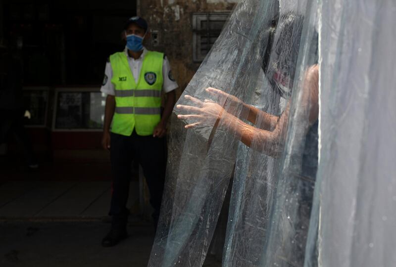 A woman wearing a protective face mask walks through a decontamination chamber in the neighborhood of Petare in Caracas, Venezuela. AP Photo