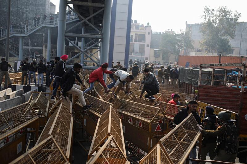 Protesting farmers jump police barricades tp march to the capital during India's Republic Day celebrations in New Delhi. AP