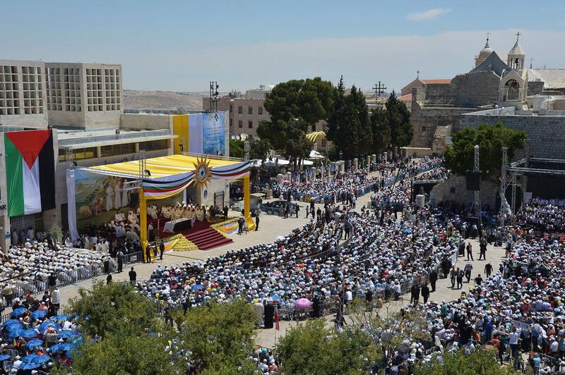 People attend an open-air mass led by Pope Francis at the Manger Square on May 25, 2014 outside the Church of the Nativity in the West Bank Biblical town of Bethlehem. Pope Francis arrived in Bethlehem to begin the most sensitive part of his three-day Middle East tour aimed at forging regional peace and easing an age-old rift within Christianity. Vincenzo Pinto/AFP Photo