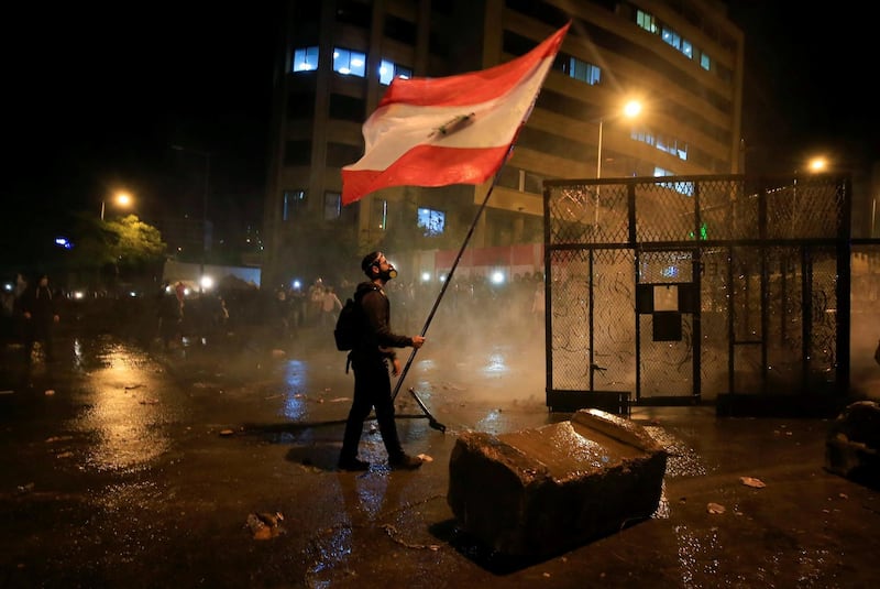 A demonstrator holds the Lebanese flag during a protest against the newly formed government outside the prime minister’s office in downtown Beirut. Reuters