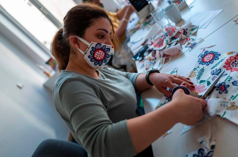 A refugee from Kurdistan cuts fabric for face covers in Berlin on April 23, 2020, amid a new coronavirus Covid19 pandemic. Men and women refugees from Afghanistan, Iran and Kurdistan are producing face covers by the hundreds at the GIZ (Gesellschaft für Interkulturelles Zusammenleben) offices in Berlin's western district of Spandau.  Many refugees, who arrived in Germany by the thousands in 2014 and 2015, are finding ways to help out during the current pandemic.  / AFP / John MACDOUGALL
