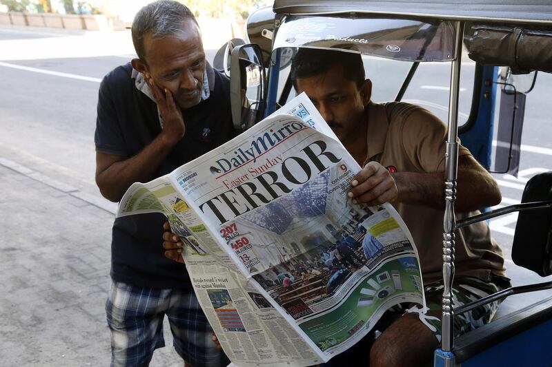 People read a newspaper the day after blasts killed hundreds in Colombo.  EPA
