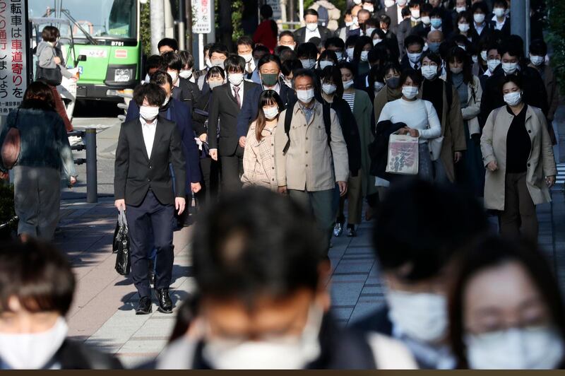 Commuters wearing face masks to protect against the spread of the coronavirus walk on a street in Tokyo. The pandemic is continuing to worsen, with rising coronavirus counts across the United States and Europe pushing governments to bring back varying degrees of restrictions on businesses. AP Photo