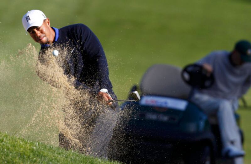 Tiger Woods (L) of the U.S. hits out of the sand trap on the fifth hole as Casey Martin (R) of the U.S. gets out of his golf cart during a practice round for the 2012 U.S. Open golf championship on the Lake Course at the Olympic Club in San Francisco, California June 12, 2012. Martin, who has a condition which makes it hard for him to walk long distances, won a landmark Supreme Court decision that allowed him to play with the use of a golf cart on the PGA tour. REUTERS/Matt Sullivan (UNITED STATES  - Tags: SPORT GOLF)  