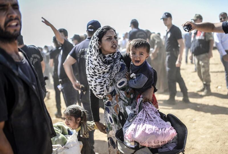 A Syrian Kurdish woman crosses the border into Turkey at the town of Suruc, Sanliurfa. Bulent Kilic / AFP