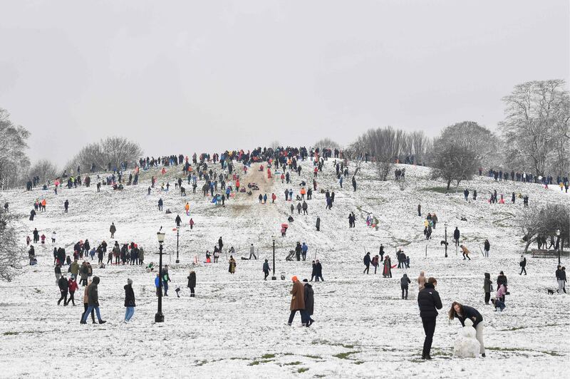 People play in the snow on Primrose Hill in London, as the capital experiences a rare covering of snow on Sunday. AFP