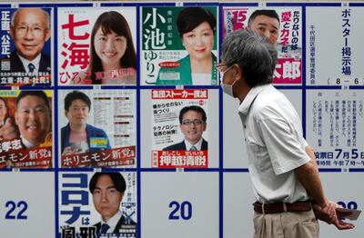 A voter wearing a protective face mask watches candidate posters, including current governor Yuriko Koike, for the Tokyo Governor election in front of a voting station amid the coronavirus disease (COVID-19) outbreak, in Tokyo, Japan July 5, 2020.  REUTERS/Issei Kato