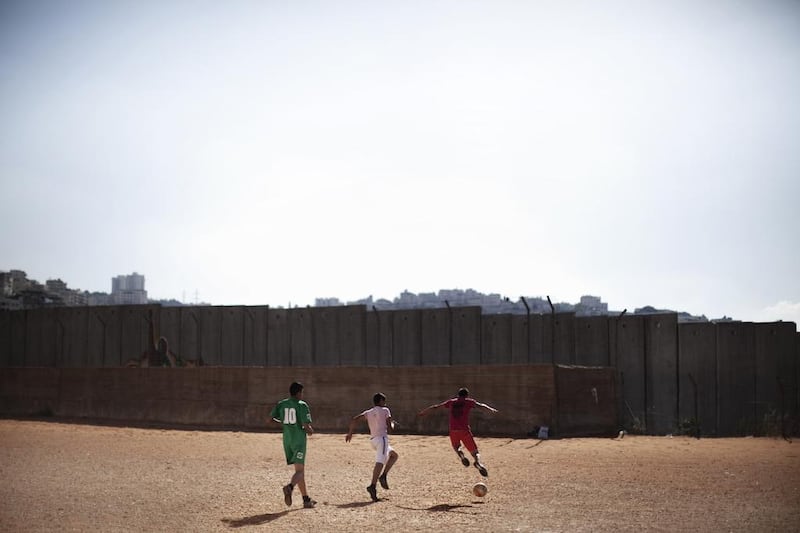 Palestinian boys play football in front of the controversial Israel separation barrier in the West Bank village of Anata. (Marco Longari / AFP)

