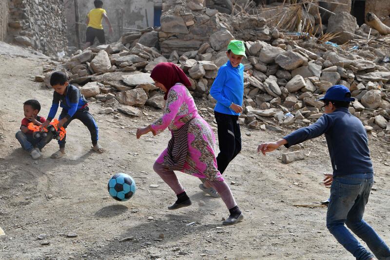 Children play football beside the rubble of collapsed homes in the village of Afella Igir in the Amizmiz region of Morocco. AFP