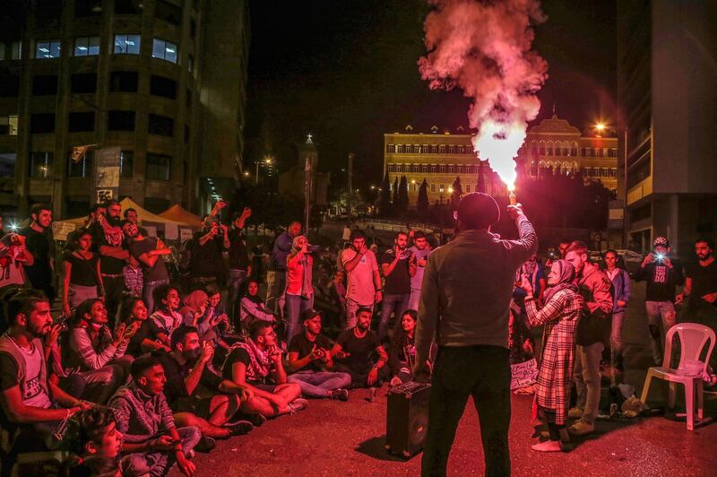 A protester lights a flare, as others chant and dance at national songs during ongoing anti-government protests in front the government palace in downtown Beirut, Lebanon. EPA