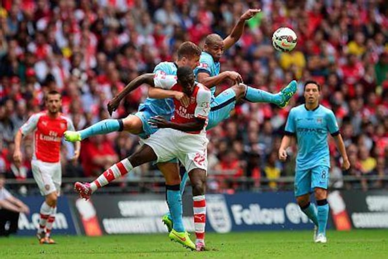 Arsenal's French striker Yaya Sanogo, centre, goes up for a high ball with Manchester City's Brazilian midfielder Fernando, right, and Manchester City's Serbian defender Aleksandar Kolarov during the FA Community Shield football match between Arsenal Manchester City at Wembley Stadium in north London on August 10, 2014. AFP PHOTO / CARL COURT