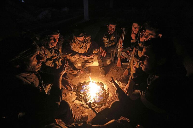 Turkish-backed Syrian fighters gather around fire in the town of Sarmin, about 8 kilometres southeast of the city of Idlib in northwestern Syria.   AFP