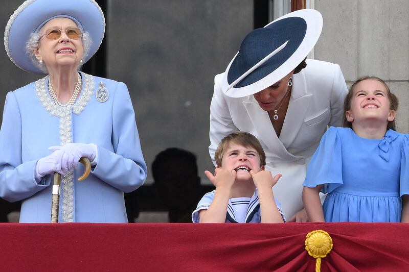 Kate, Duchess of Cambridge, second right, talks to Prince Louis who is pulling a funny face, as they stand with the queen and Princess Charlotte to watch a special flypast from the Buckingham Palace balcony. AFP