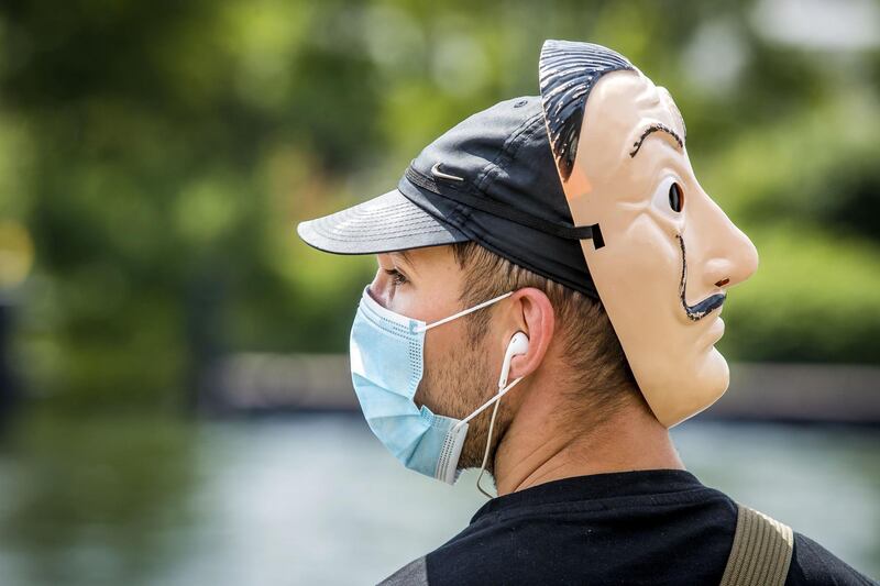 An activist wears a protective face mask and a Salvador Dali mask at the back of his head as people form a human chain in the centre of Maastricht, The Netherlands.  AFP