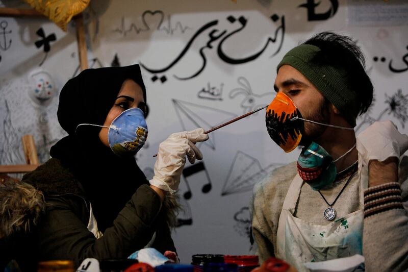 Palestinian artist Samah Said (L) paints a dust mask worn by fellow artist Dorgham Krakeh (R) for a project raising awareness about the COVID-19 coronavirus pandemic, in Gaza City.   AFP