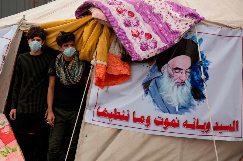 Anti-government demonstrators wearing protective masks stand at the entrance of a tent in the southern Iraqi city of Basra. AFP