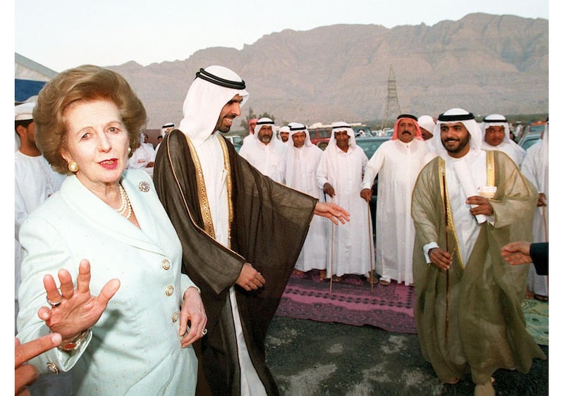British former Prime Minister Baroness Margaret Thatcher (L) protests against having her picture taken as she walks alongside Sheikh Faysal Bin Saqr Al Qasimi (2L), chairman of the new free trade zone in Ras Al Khaimah emirate, 24 March. Al-Qasimi danced a traditional Bedouin dance with the former British Prime Minister, who is in the emirate for the opening of an exhibition for British companies.. (Photo by RABIH MOGHRABI / AFP)