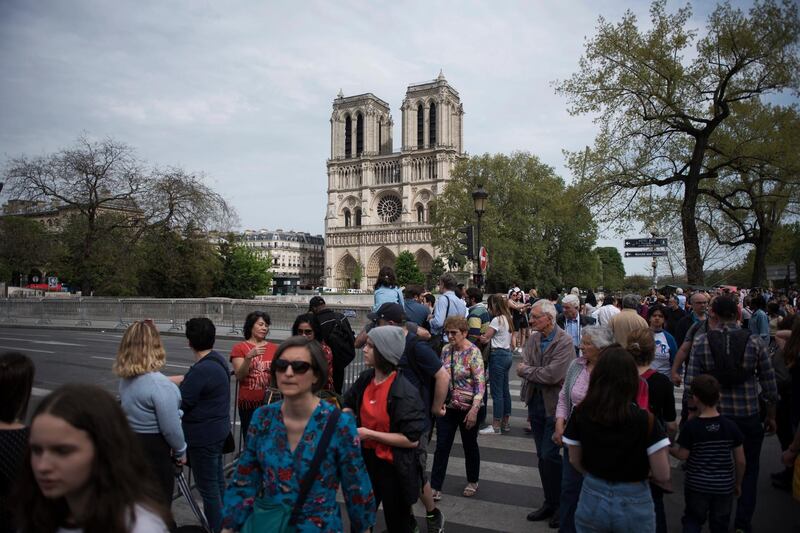 epa07521530 Tourists walks front of Notre Dame de Paris after a new smaller security area was applied by the French police in Paris, France, 22 April 2019. A fire started in the late afternoon 15 April in one of the most visited monuments of the French capital.  EPA/Julien de Rosa