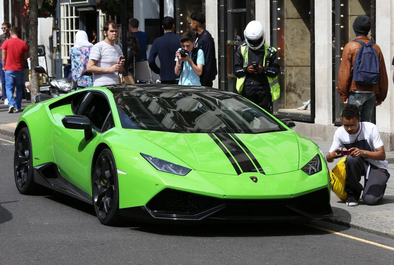 LONDON 18th July 2015. The Carparazzi gather around a Lamborghini super car parked illegally in Knightsbridge, London,  as a parking attendant starts to issue a ticket.   Stephen Lock for the National  FOR NATIONAL  *** Local Caption ***  SL-supercar-004.JPG